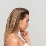 Side profile of an elegant woman with long hair wrapped in a towel, capturing natural beauty.