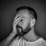 Expressive black and white portrait of a bearded man showing stress and contemplation.