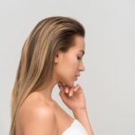 Side profile of an elegant woman with long hair wrapped in a towel, capturing natural beauty.