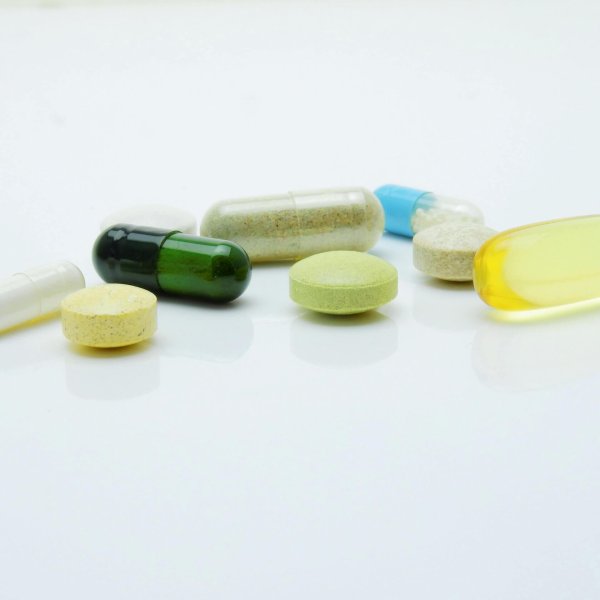 Close-up of various pills and capsules arranged on a white surface, representing healthcare and medicine.