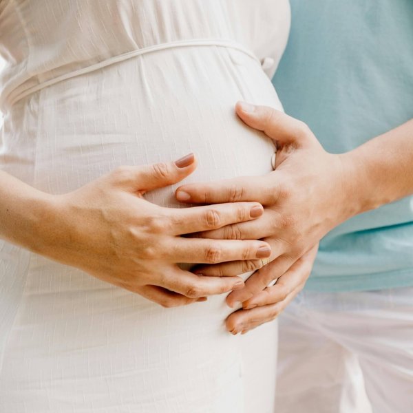 Close-up of hands gently embracing a baby bump in a warm, serene setting.